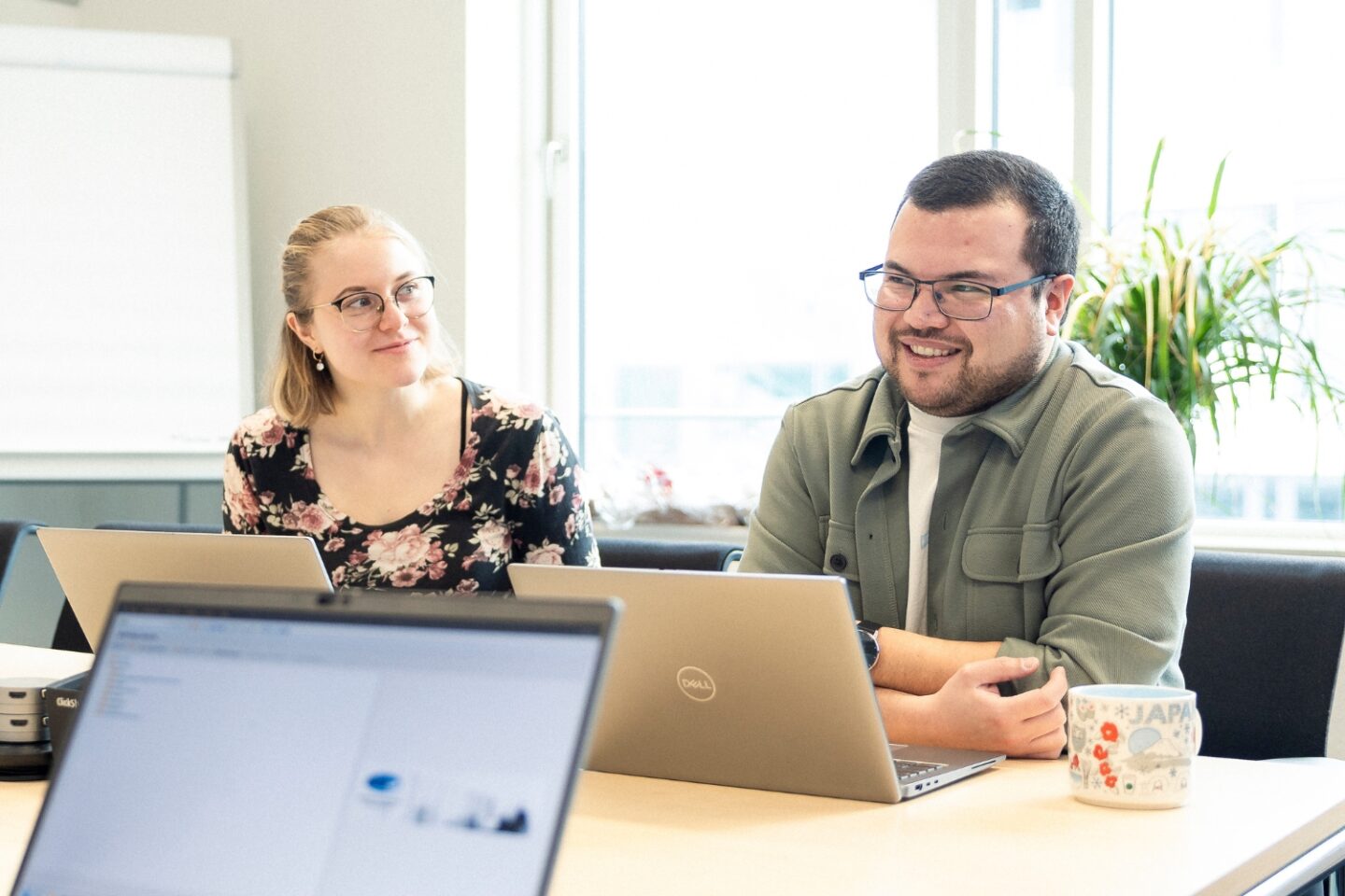 Zwei Personen schauen Richtung Laptop und unterhalten sich miteinander.